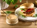 Pyszny sos do burgera w słoiczku, obok apetycznego burgera z dodatkami. Idealny do każdej kanapki.