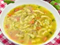 Aromaticzna zupa zacierkowa z kawałkami marchewki i świeżym koperkiem, podana w białej misce na czerwono-białej kratce.