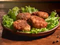 Cztery apetyczne kotlety mielone z airfryer, podane na liściach sałaty. Idealne na szybki obiad.