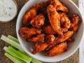 Chrupiące skrzydełka z airfryer w misce, obok sosu serowego i łodyg selera. Idealna przekąska!