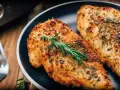 Dwa soczyste filety z kurczaka z airfryer, przyprawione ziołami i podane z gałązką rozmarynu.