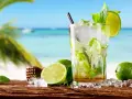 Orzeźwiający mojito na plaży, z limonkami i miętą, w tle błękitne morze i palmy. Idealny na upalny dzień.