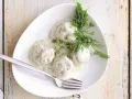 Pulpeciki w kremowym sosie koperkowym, podane na białym talerzu z widelcem. Pyszny sos do pulpetów.