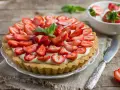 Tarta z truskawkami i kremem, ozdobiona listkami mięty.