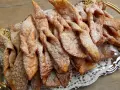 Chrupiące faworki, przepis babci, posypane cukrem pudrem, ułożone na ozdobnej tacy.