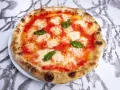 Pyszne ciasto na pizzę neapolitańską z sosem pomidorowym, mozzarellą i bazylią. Idealna na szybki lunch.