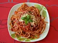 Pyszny sos do makaronu spaghetti z tartym serem i bazylią na talerzu.