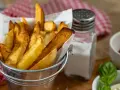 Złociste frytki w metalowym wiaderku, obok solniczka i ketchup. Czy ziemniaki sałatkowe nadają się na frytki? Wyglądają pysznie!