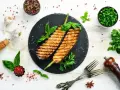 Grillowane bakłażany z bazylią i pietruszką, idealne na nietypowe dania z grilla. Obok przyprawy, czosnek i oliwa.