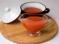 Pomarańczowy sos do chińszczyzny w szklanej sosjerce i czarnej miseczce, obok biała pokrywka.