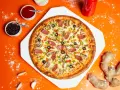 Pizza z kiełbasą, pieczarkami i oliwkami na pomarańczowym tle, obok sosy i imbir.