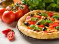 Pyszna pizza z pomidorami, oliwkami i kukurydzą, obok świeże pomidory i bazylia. Ile piec pizze?