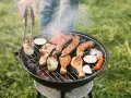 Pyszne kiełbaski i kurczak pieką się na grillu, a dym unosi się w powietrzu. Idealny sposób, jak rozpalić grilla i cieszyć się latem.