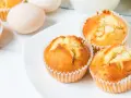 Złociste babeczki z airfryer na białym talerzu, obok jajka. Idealne na szybką przekąskę.