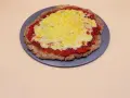 Pizza z chleba tostowego z sosem pomidorowym i roztopionym serem na ciemnej tacy.