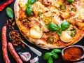 Apetyczna pizza z kiełbasą, cebulą i papryczkami jalapeño, otoczona składnikami.