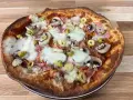Apetyczna pizza z twarogu z pieczarkami, szynką i oliwkami, z ciągnącym się serem.