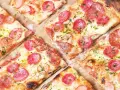 Kawałki pysznej pizzy cienkie ciasto z kiełbasą i serem, posypane ziołami. Idealna na szybką przekąskę.