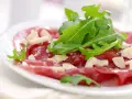 Cienkie plastry wołowiny z rukolą i parmezanem, polane pysznym sosem do carpaccio.