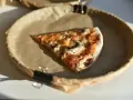 Kawałek pizzy z pieczarkami na brązowym papierze. Zastanawiasz się, ile kalorii ma pizza?