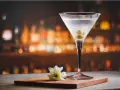 Kryształowy kieliszek z martini, trzema oliwkami i białą kwiatową ozdobą. Idealny drink, z czym pić martini?