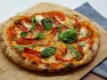 Pyszna pizza z rukolą, pomidorkami, papryczką i salami. Idealne składniki na pizzę, które zachwycą każdego smakosza.