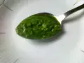 Łyżeczka pełna aromatycznego pesto z pietruszki, gotowa do podania.