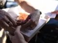 Dwie osoby dzielą się pizzą z pudełka. Właśnie pokazują sobie, jak jeść pizzę, by każdy dostał swój kawałek.