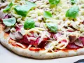 Gotowy do pieczenia przepis na ciasto do pizzy: sos pomidorowy, salami, pieczarki, ser i świeża bazylia.