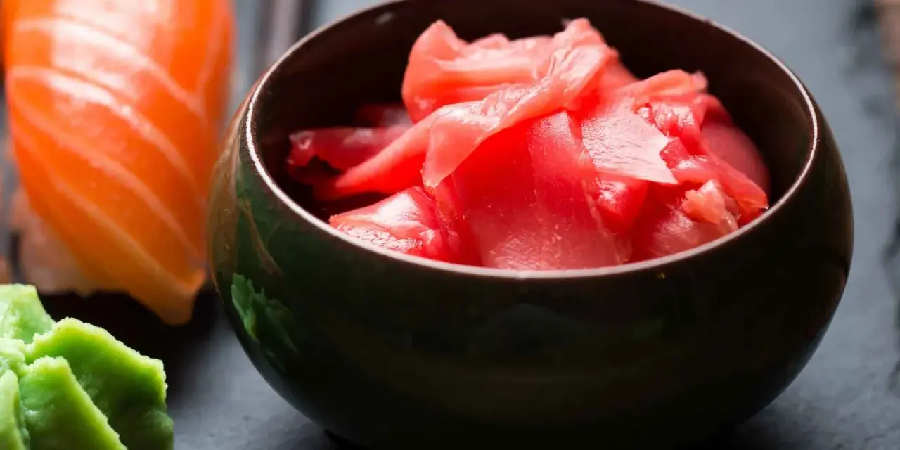 Miseczka z różowym, marynowanym imbirem obok sushi i wasabi. Idealny dodatek do japońskich potraw.