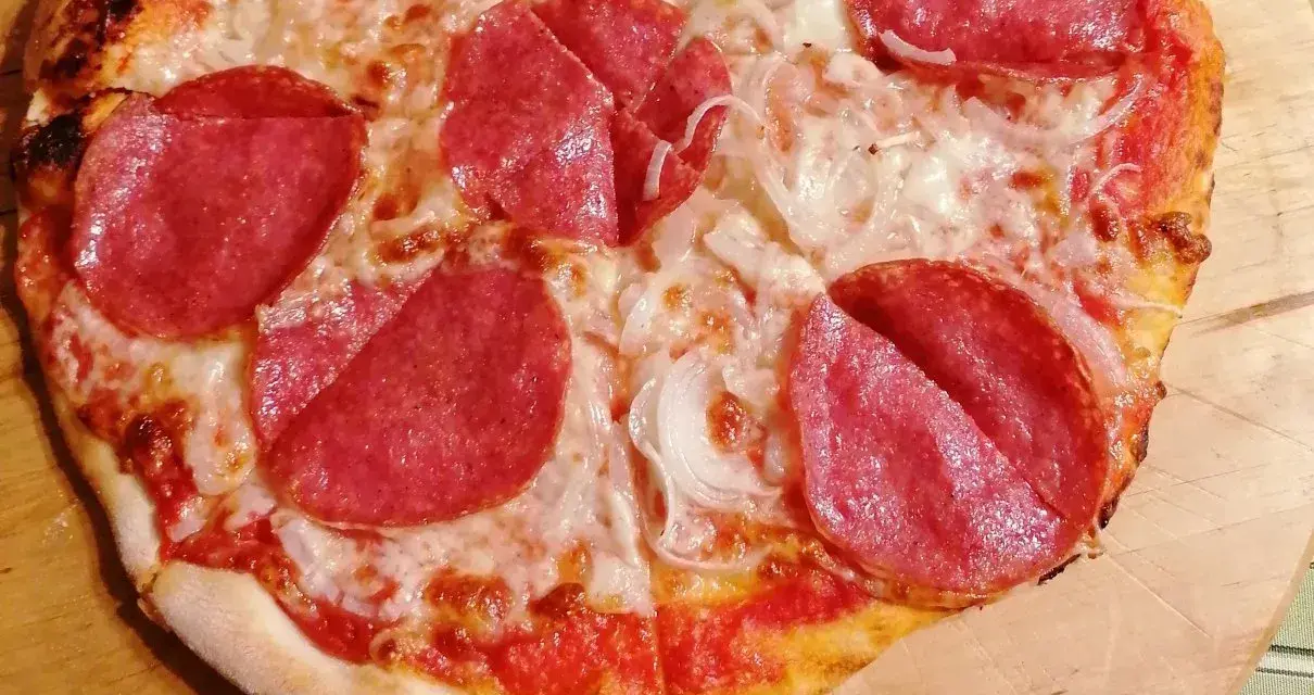 Pyszna pizza salami z serem i cebulą, idealna na szybki obiad.