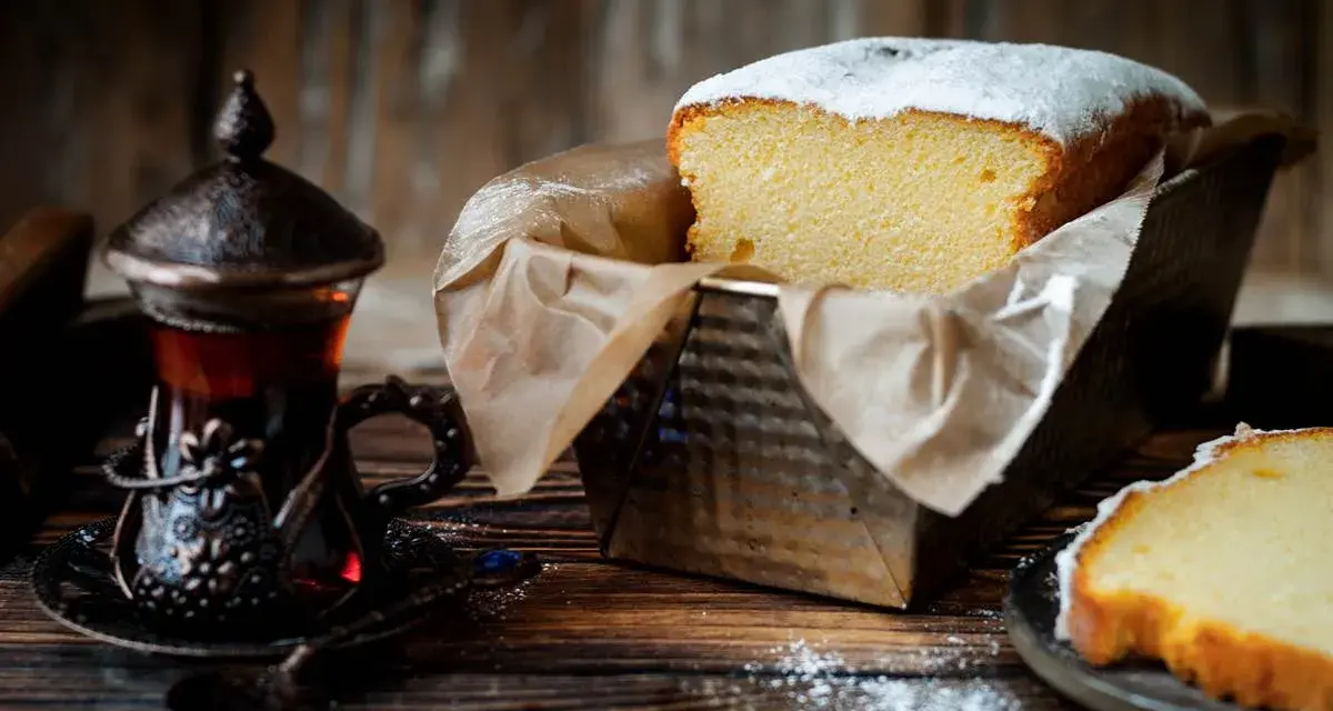 Wilgotna babka w keksówce, oprószona cukrem pudrem, obok paruje herbata w orientalnej filiżance. Idealny deser na chłodne popołudnie.