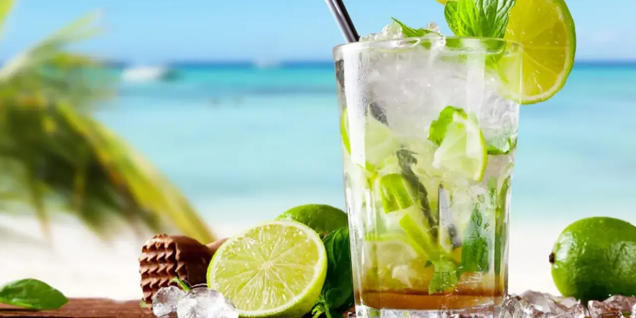 Orzeźwiający mojito na plaży, z limonkami i miętą, w tle błękitne morze i palmy. Idealny na upalny dzień.