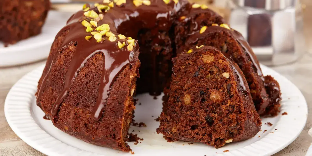 Wilgotna babka czekoladowa z orzechami, polana polewą i posypana pistacjami. Idealna na szybki deser.