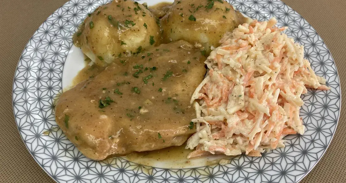 Pyszna pierś z kurczaka w sosie własnym, podana z ziemniakami i surówką z marchewki i kapusty.