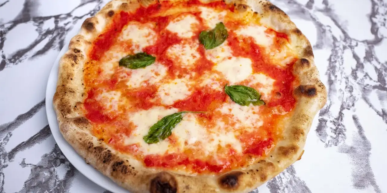 Pyszne ciasto na pizzę neapolitańską z sosem pomidorowym, mozzarellą i bazylią. Idealna na szybki lunch.