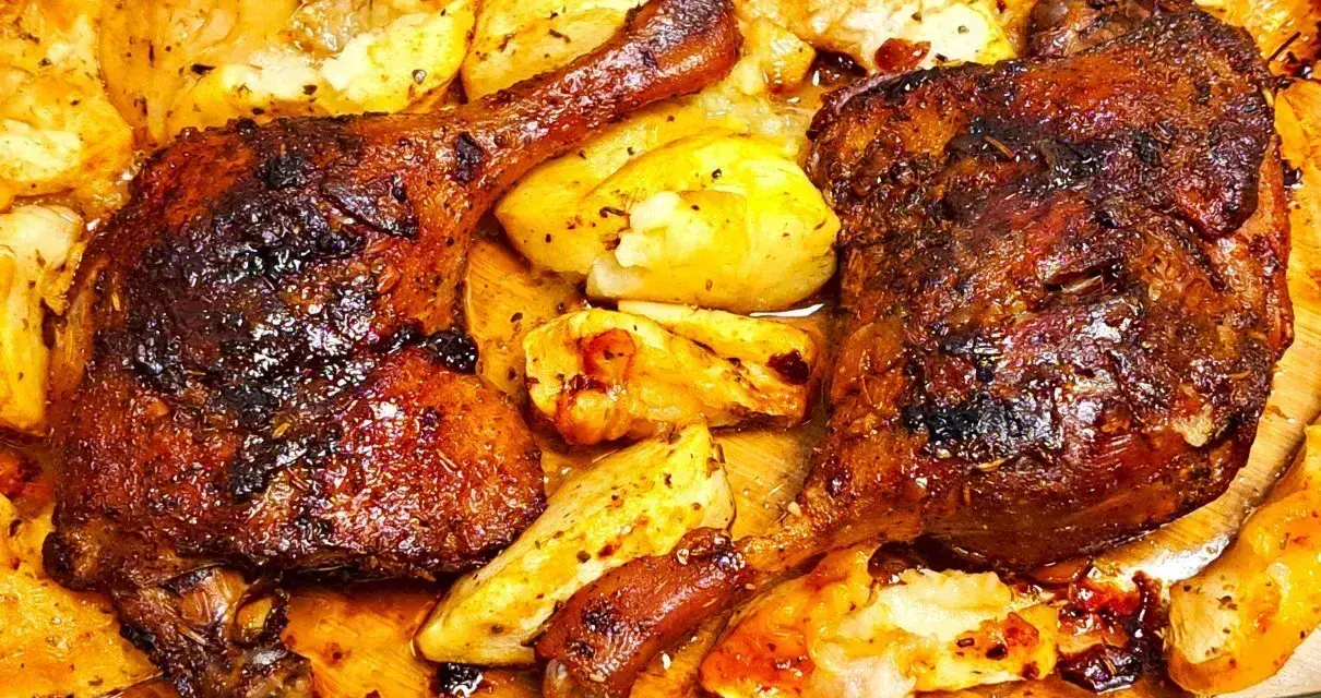 Pyszne, pieczone udka z kaczki z chrupiącymi ziemniakami, skąpane w aromatycznym sosie.