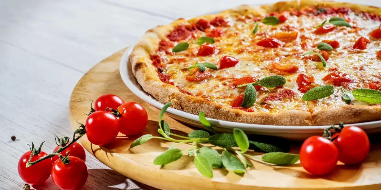 Apetyczna pizza z pomidorkami i bazylią. Czy zastanawiałeś się, dlaczego pizza jest niezdrowa?