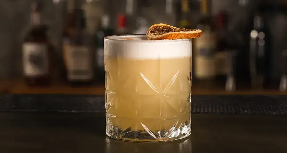 Klasyczny whisky sour przepis: orzeźwiający koktajl z pianką i plasterkiem suszonej pomarańczy. Idealny na każdą okazję.
