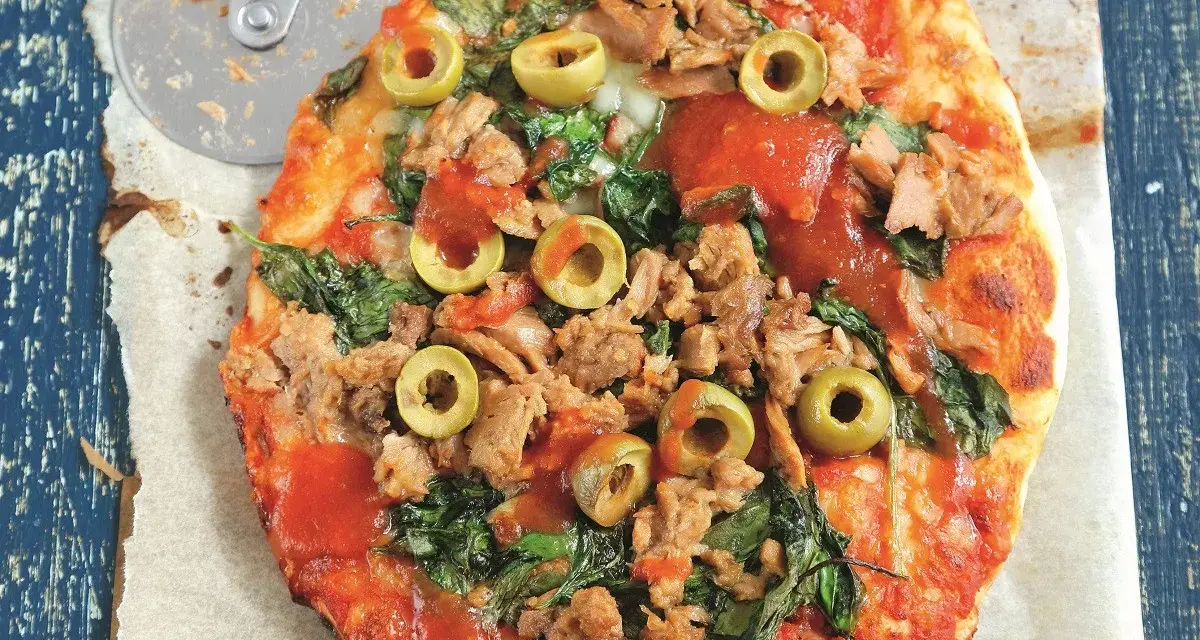 Pyszna pizza z tuńczykiem, szpinakiem i oliwkami, gotowa do pokrojenia.