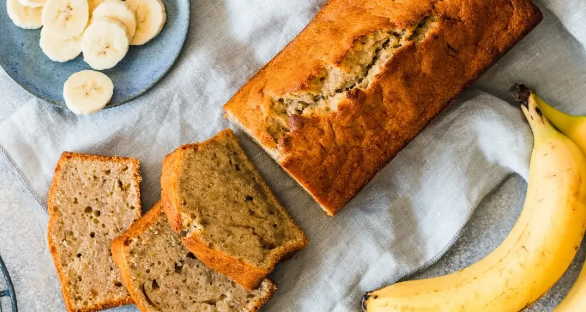 Pyszny, domowy chlebek bananowy – sprawdzony przepis na wilgotne ciasto. Obok kromki i plasterki banana.