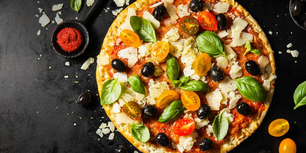 Pizza z pomidorkami, oliwkami i bazylią. Pomidorowe pesto to niezbędny dodatek smakowy włoskiej pizzy.