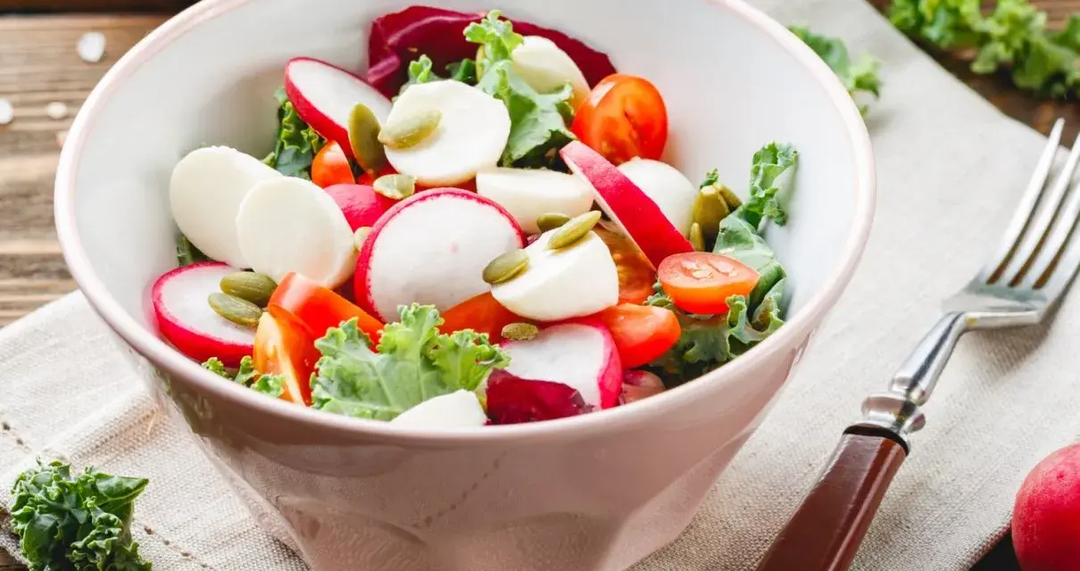 Świeża sałatka do grilla w 3 minuty: rzodkiewka, pomidorki, ser mozzarella i pestki dyni w misce.