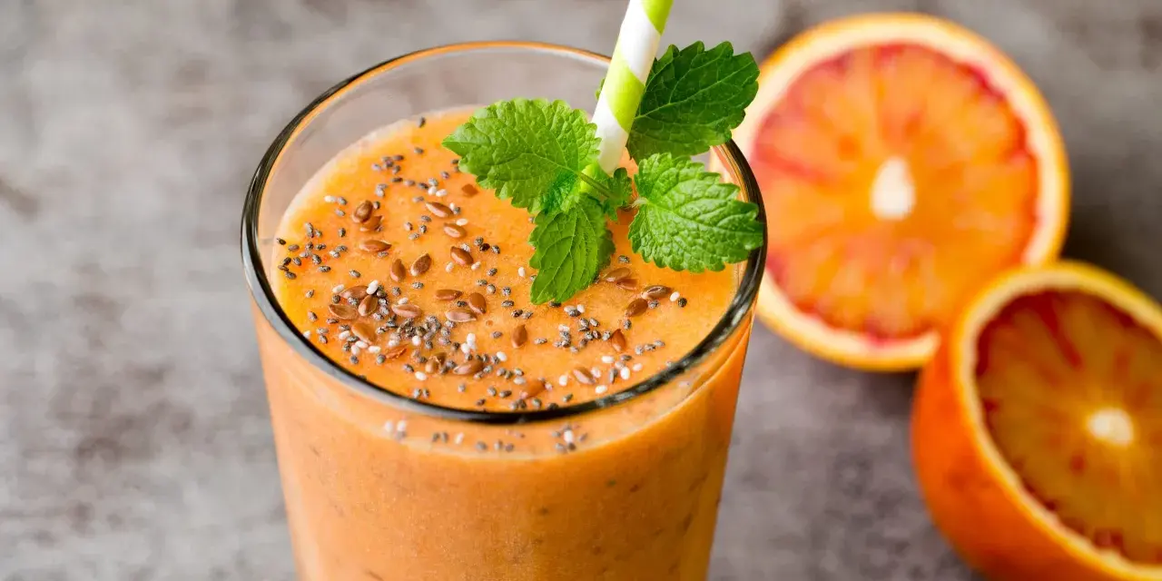 Pomarańczowy smoothie z nasionami chia i siemieniem lnianym, ozdobione miętą. Idealne na zdrowe śniadanie. Inspiracja na smoothie przepisy.