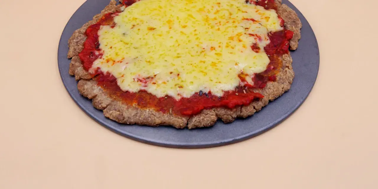 Pizza z chleba tostowego z sosem pomidorowym i roztopionym serem na ciemnej tacy.