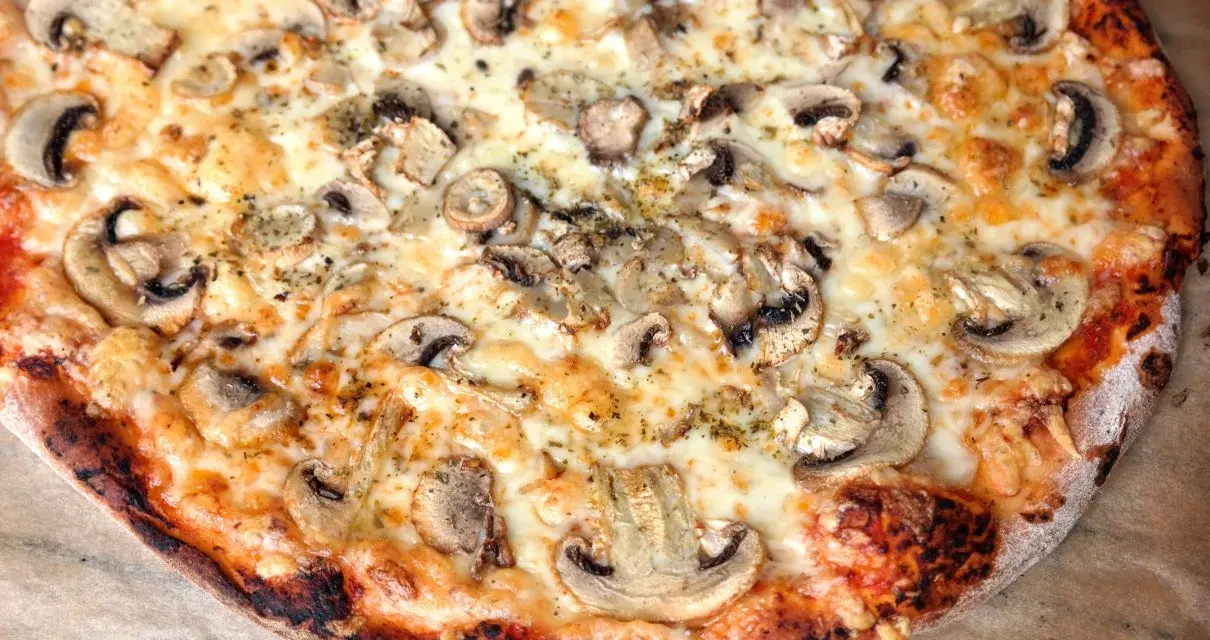Pyszna pizza włoska z pieczarkami i ciągnącym serem. Idealny przepis na domową ucztę.