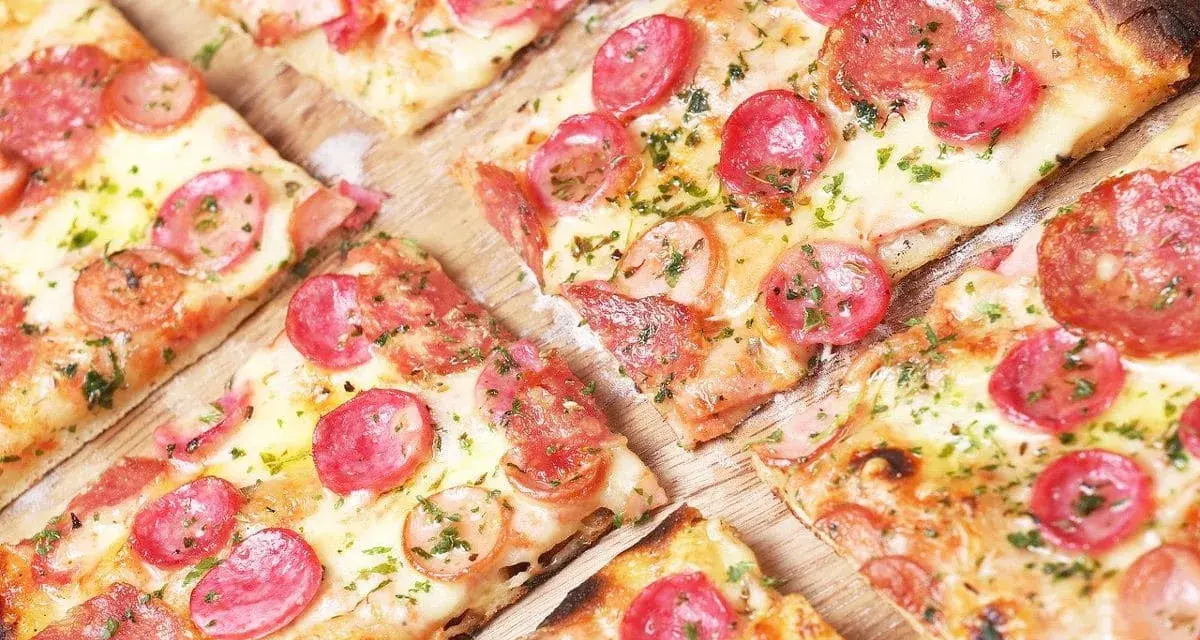 Kawałki pysznej pizzy cienkie ciasto z kiełbasą i serem, posypane ziołami. Idealna na szybką przekąskę.