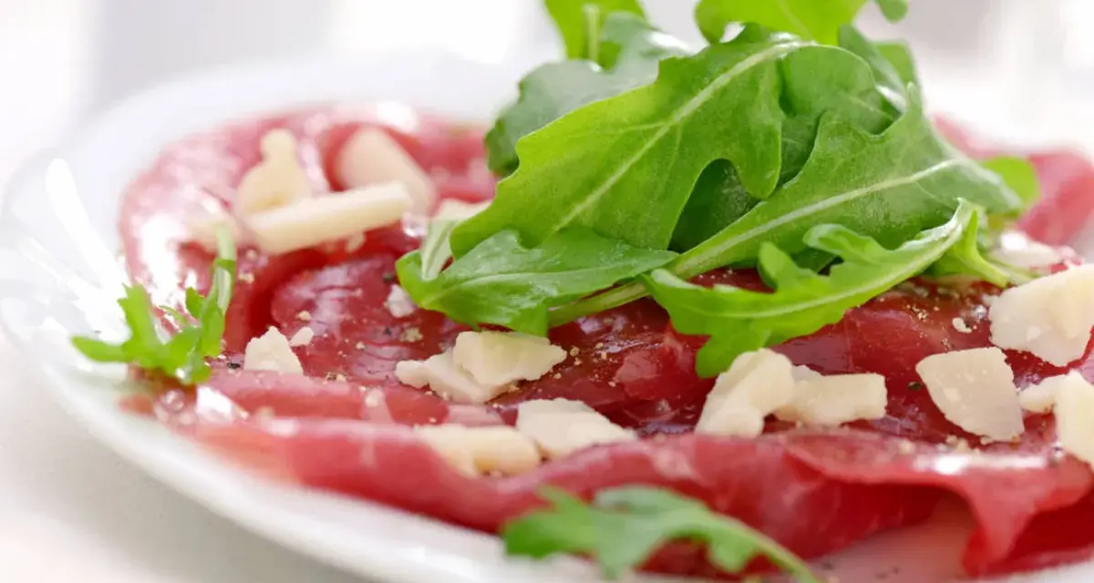 Cienkie plastry wołowiny z rukolą i parmezanem, polane pysznym sosem do carpaccio.