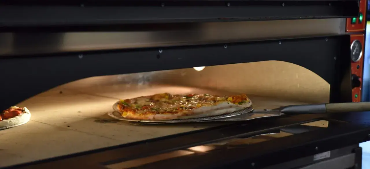 Pieczenie pizzy w piecu. Czy pizzę można zamrozić? Ta gorąca, parująca pizza na łopacie sugeruje, że świeżość jest kluczowa.