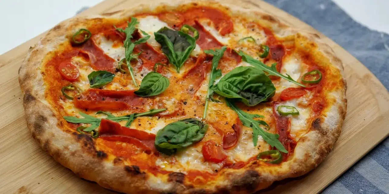 Pyszna pizza z rukolą, pomidorkami, papryczką i salami. Idealne składniki na pizzę, które zachwycą każdego smakosza.